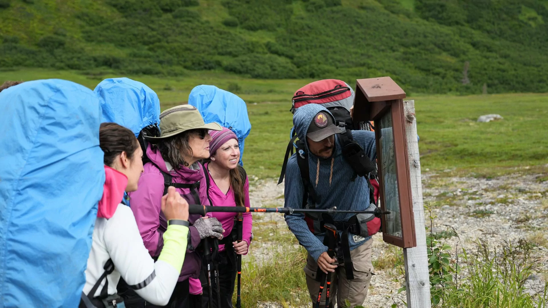A hiking guide and a group of women point to a trail sign