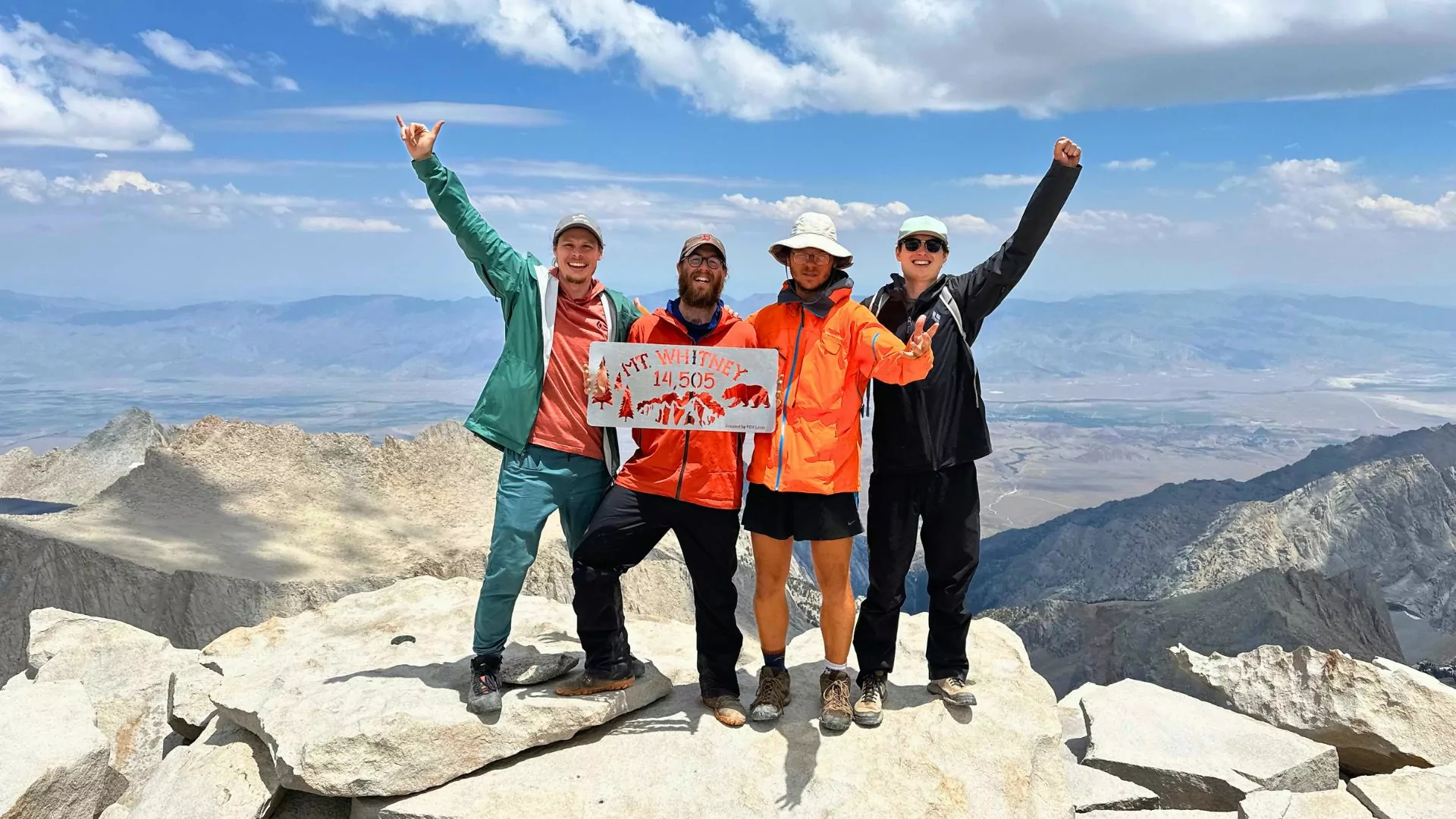 Four young men pose on the summit of Mount Whitney at the culmination of the John Muir Trail